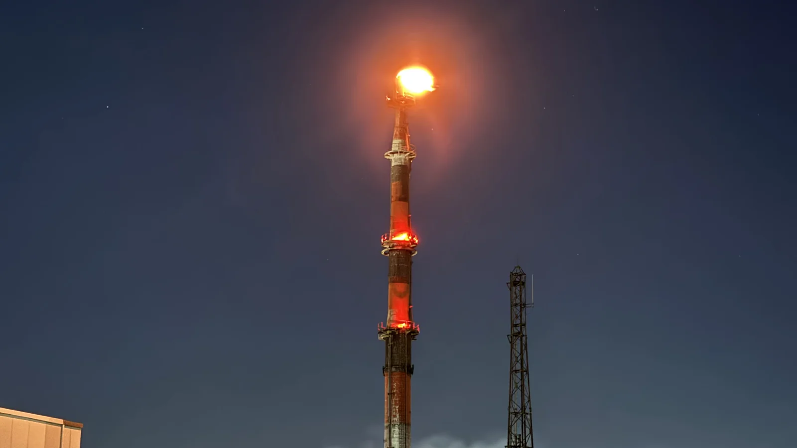 川崎の石油化学コンビナート夜景 — 巨大な煙突とフレアスタックが赤く光る工場夜景の代表