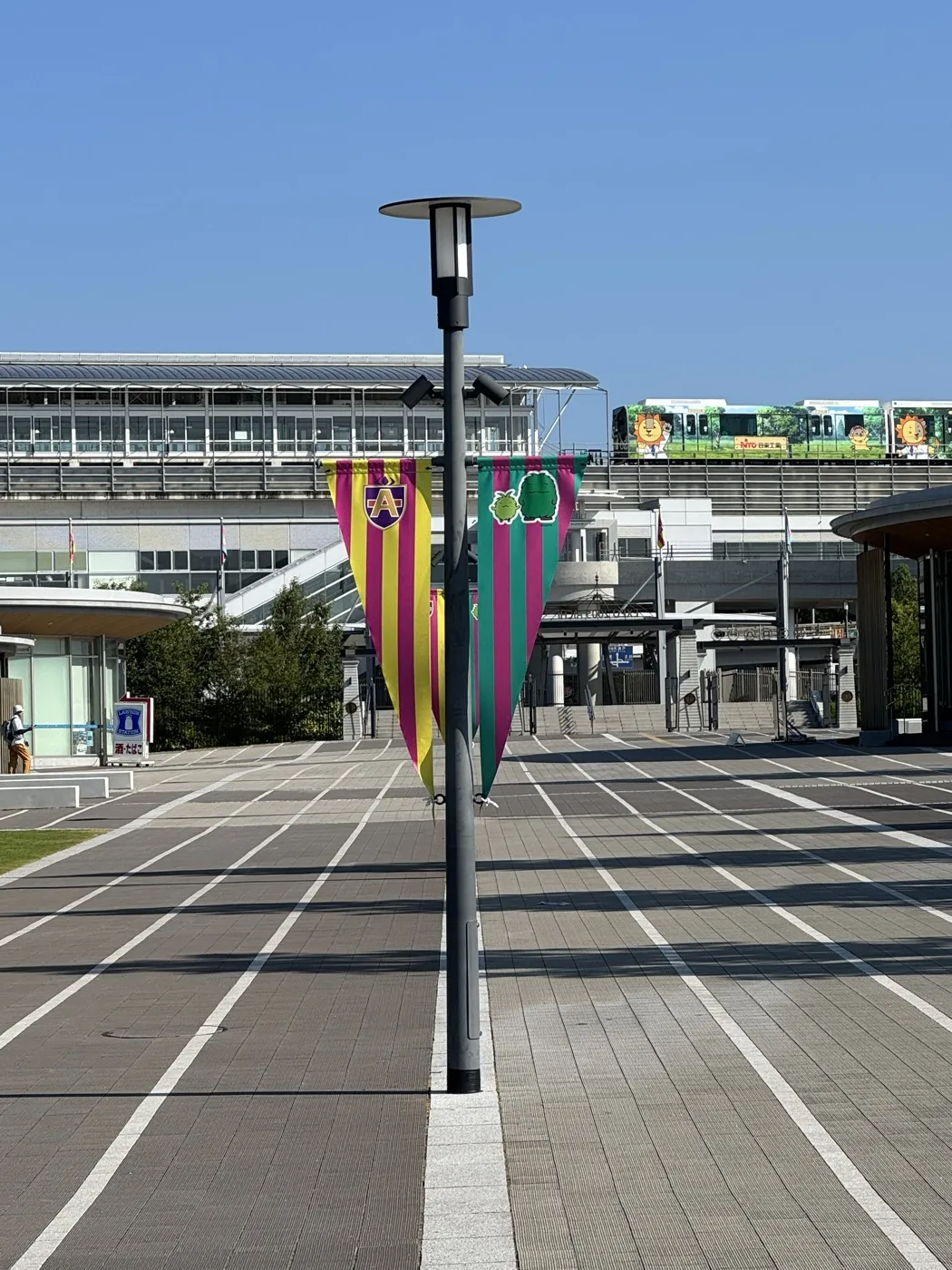 リニモ「愛・地球博記念公園」駅と公園入口の広場 — 高架を走るリニモの車両