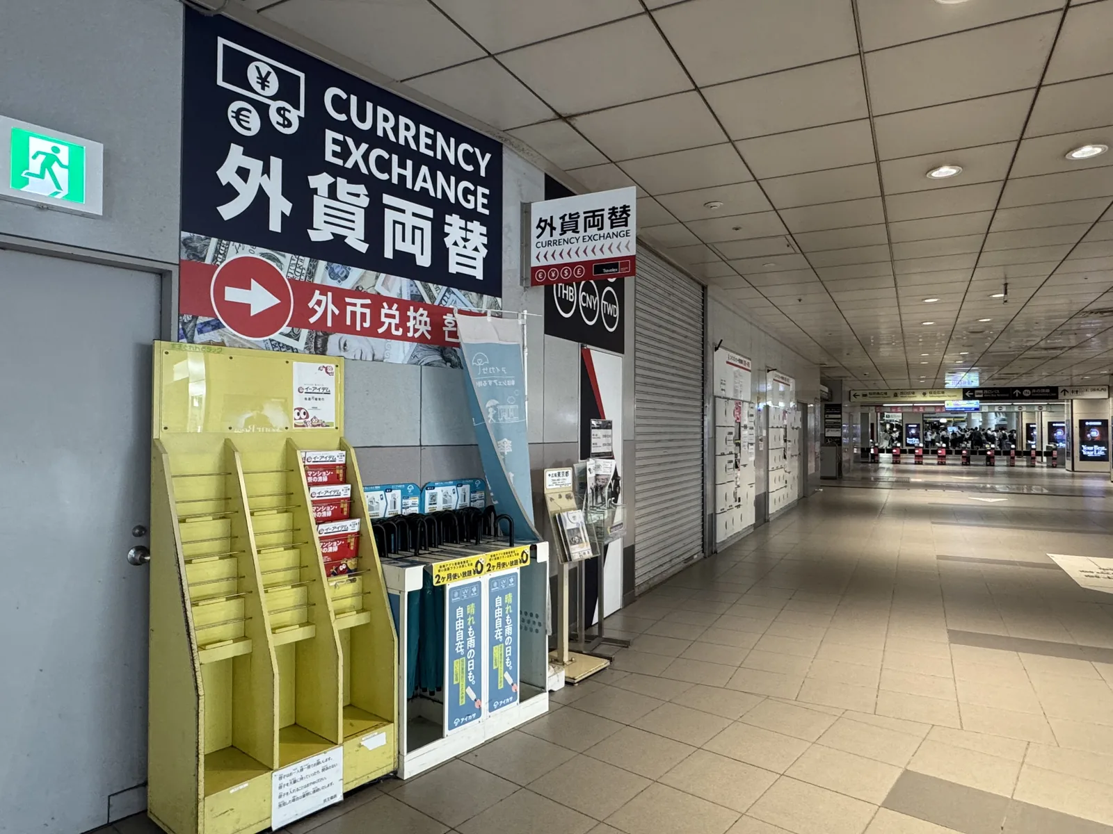 A vertical "Foreign Exchange / 外貨両替" sign over a small counter near Shibuya Crossing — handy in a pinch, but compare the posted rate before you commit