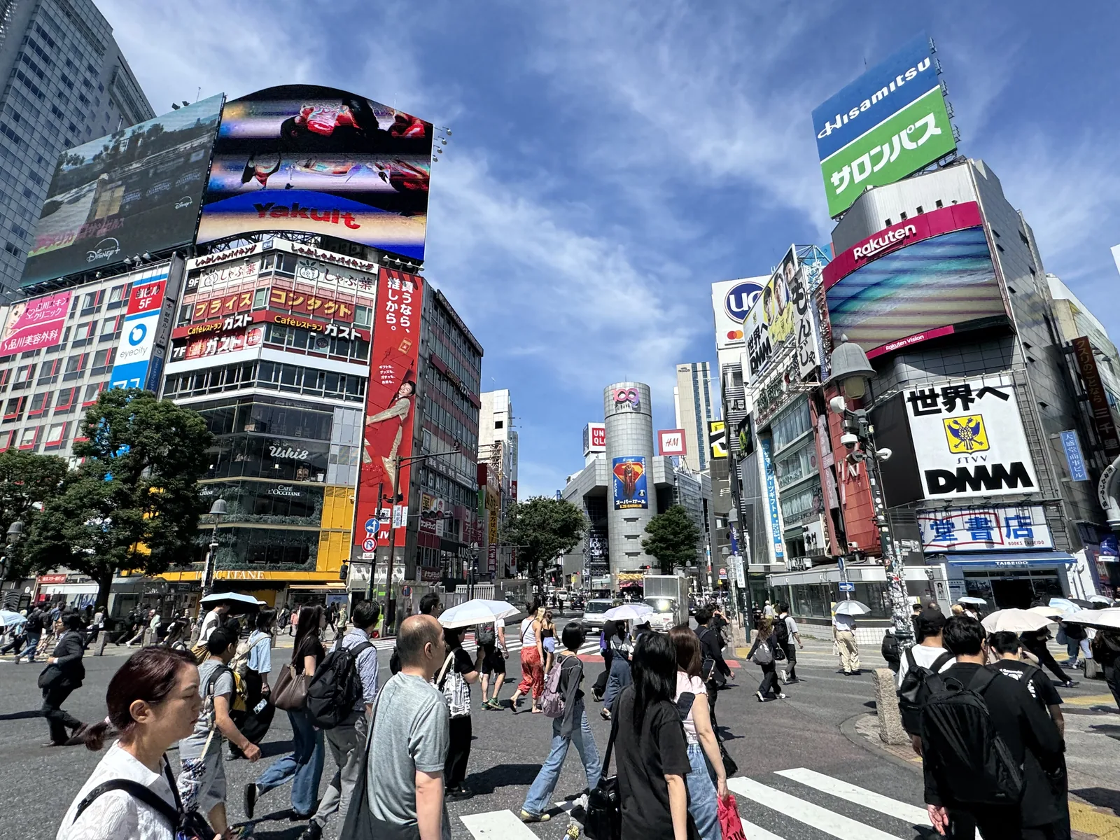 Shibuya Scramble Crossing at street level, crowds flowing across under the neon billboards — the heart of the district's exchange hunt