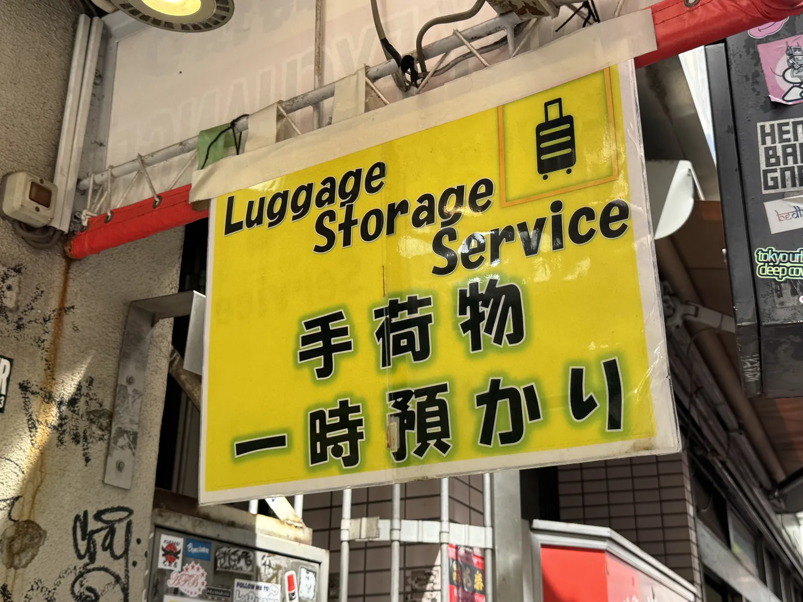 A small Shibuya money changer with a yellow EXCHANGE board that also offers luggage storage — a quick fallback when the main counters have shut for the night