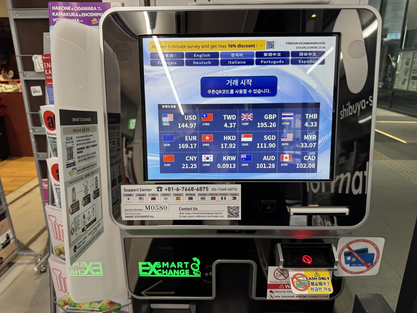 A multi-currency automated exchange kiosk in Shibuya with a green touchscreen display, accepting foreign notes and dispensing yen