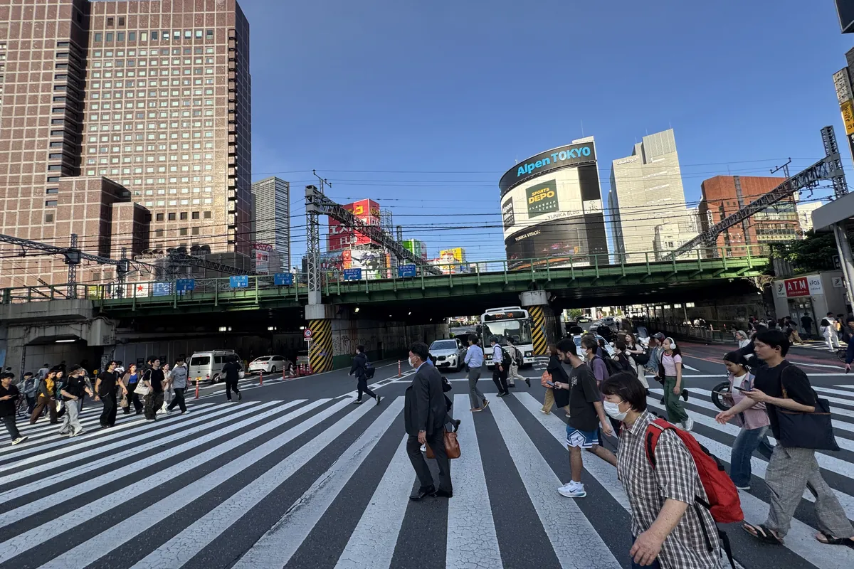 新宿西口の横断歩道 — 平日午後の人の流れ。両替店密集エリアへの動線